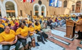 Large crowd wearing yellow shirts in front of a podium.