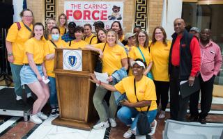 A group of people in yellow shirts standing around a podium.